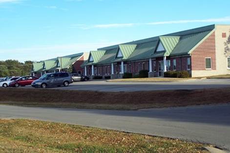 A house that has a sign on the side of a road

Description automatically generated